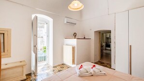 A hotel room with a bed, a small desk, a radiator, and a view of the outside. - Casa Cenzina by Rentbeat (Locorotondo)