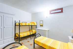 Ein Schlafsaalzimmer mit Etagenbetten, einem Schreibtisch, einem Stuhl und einem Kleiderschrank.