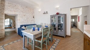 A dining area with a table, chairs, a cabinet, and a stone wall.