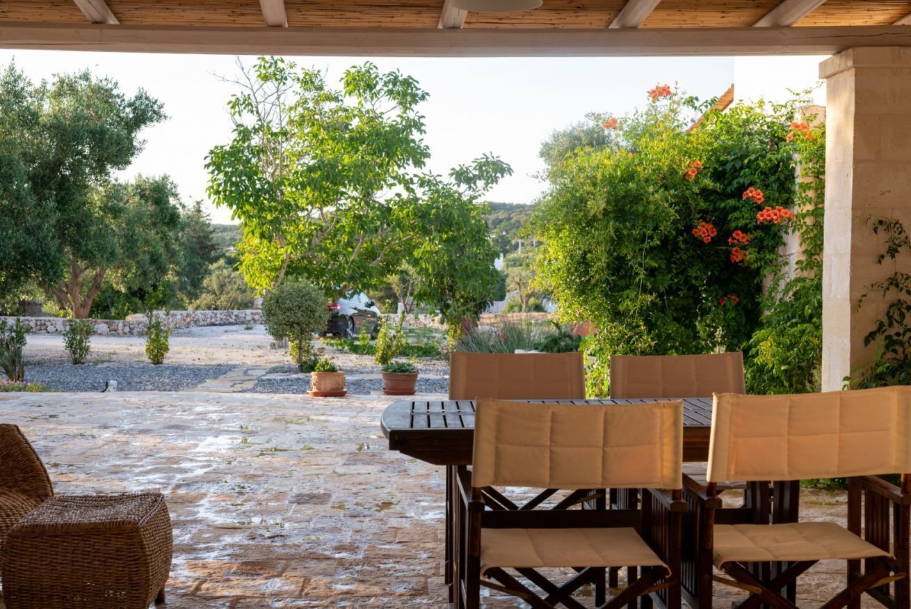 An outdoor patio with stone flooring, wicker furniture, and potted plants.