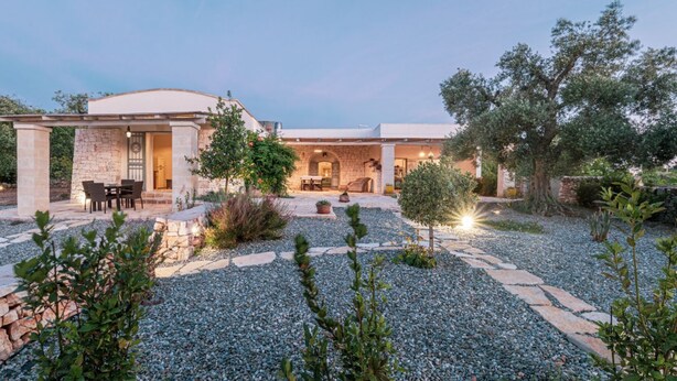 A modern house with a patio, stone pathway, and outdoor seating area.