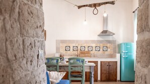A kitchen with a tiled backsplash, wooden cabinets, a teal refrigerator, and a dining area with chairs and a table.