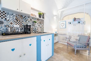 A kitchen with a checkered backsplash, a coffee machine, and a white cabinet with blue accents. - Il Vico 9 Ostuni by Rentbeat (Ostuni)