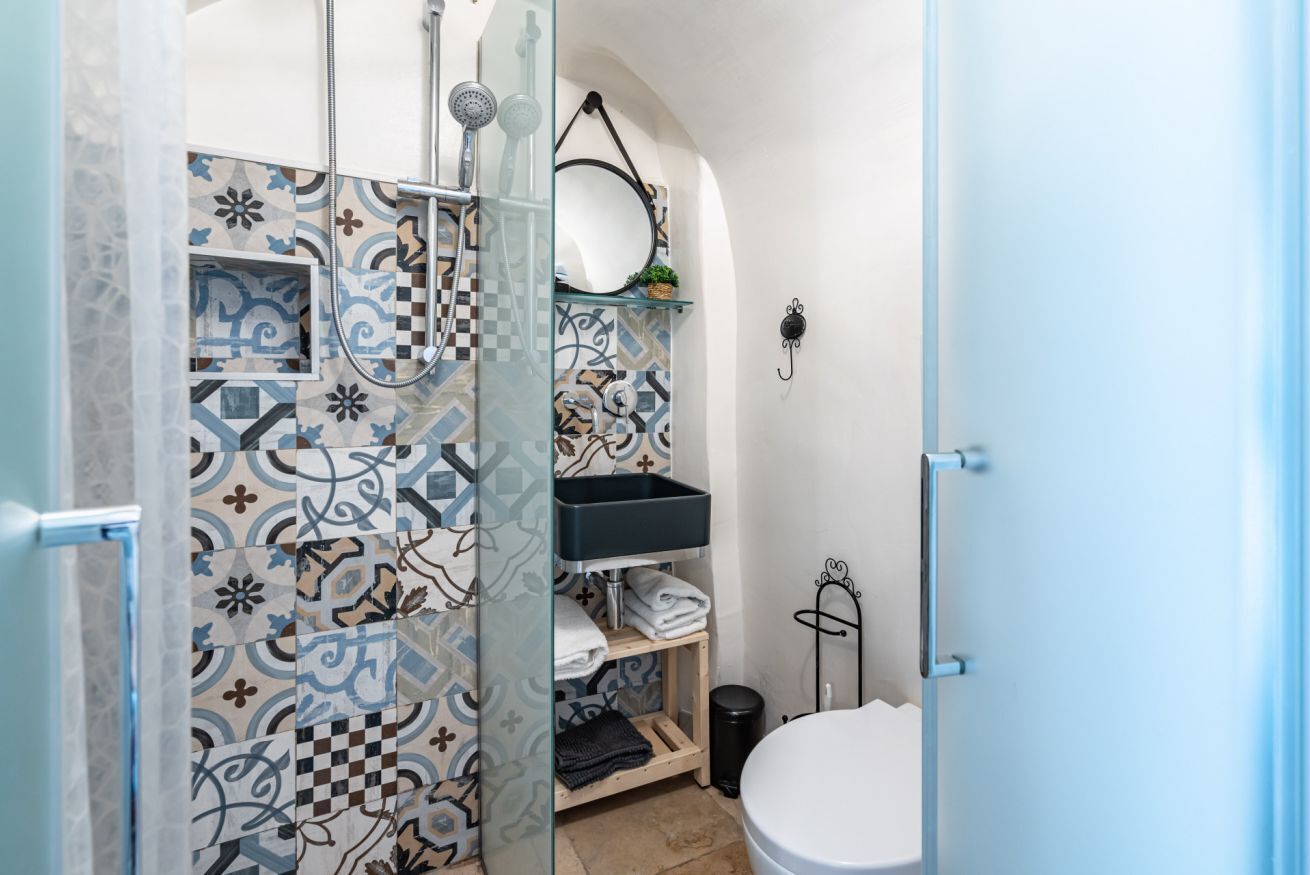 A bathroom with a shower, a sink, a toilet, and a mirror.