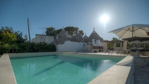 A swimming pool with stone buildings in the background. - Il Lilla by Rentbeat (Locorotondo)