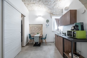 Una cucina funzionale con una parete in pietra, un tavolo da pranzo con sedie e un forno a microonde sul piano di lavoro.