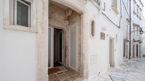 Un bâtiment avec une entrée en pierre, une porte bien visible et une rue étroite.