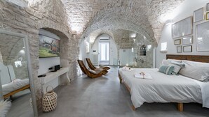 Une pièce avec un plafond en pierre, un lit, une chaise et un téléviseur.
