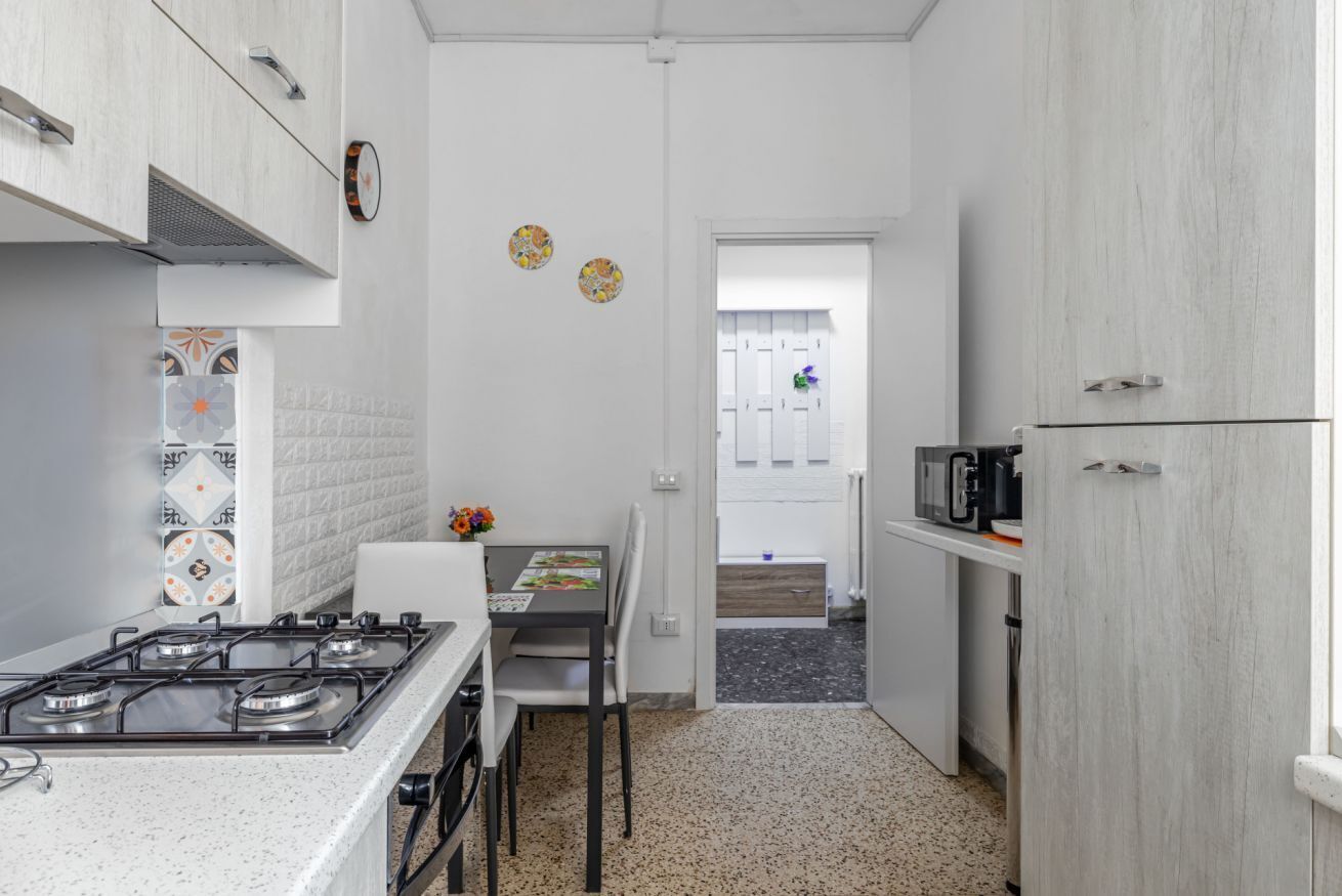 A compact kitchen with a gas stove, white cabinets, a dining table with chairs, and a microwave.