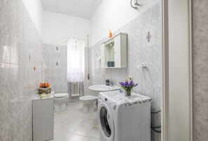 Un bagno moderno con lavatrice, WC, bidet e lavandino.