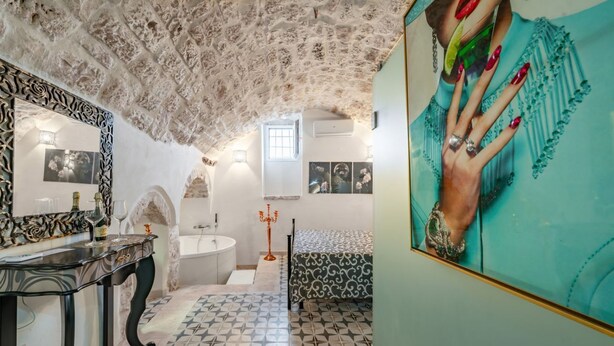 A bathroom with a patterned floor, a mirror with a decorative frame, a sink, and a window. - Donna Alfa Suite by Rentbeat (Ostuni)