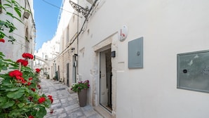 A narrow street with white buildings, a potted plant, and a door. - Donna Alfa Suite by Rentbeat (Ostuni)