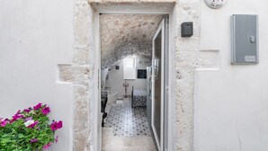 A narrow hallway leading to a room with a tiled floor and a bed. - Donna Alfa Suite by Rentbeat (Ostuni)