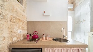 Eine kleine Küche mit Steinwand, Spüle, Wasserkocher und Kühlschrank.