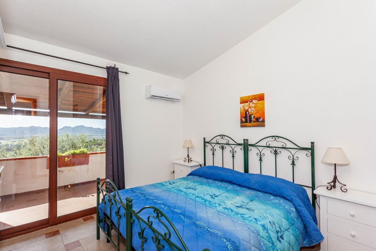 Quarto com cama, janela com vista, pintura na parede e ar condicionado.