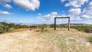 A swing set in a grassy field with a clear blue sky. - Comino Alto - Appartamento 5 by Rentbeat (Siniscola)
