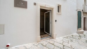 Ein Gebäudeeingang mit einem Schild, auf dem 'GATTONI LUXURY HOTEL' steht, einer Tür und einem pflasterbelagten Weg.