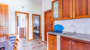 Eine Küche mit Holzschränken, einem Gaskochfeld, einer Spüle und einem Essbereich mit Tisch und Stühlen.