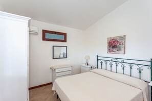 Une chambre à coucher comprenant un lit, une commode, une table de chevet, un miroir et un tableau accroché au mur.