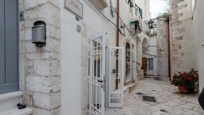 A narrow stone-paved alleyway with white doors and a post box.