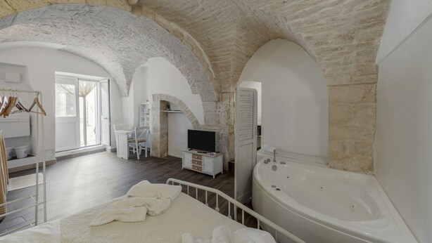 A spacious bedroom with a large bed, a sitting area with a TV, and a bathroom with a bathtub.