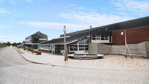 A modern building with a large glass facade, a brick wall, and a circular outdoor seating area. - 1 bedroom gorgeous apartment in Fanø (Fanø)