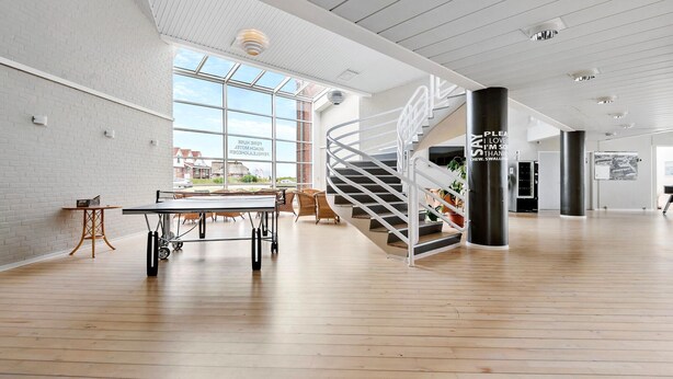 A spacious indoor area with a modern staircase, a ping pong table, and a view of the outside. - 1 bedroom gorgeous apartment in Fanø (Fanø)