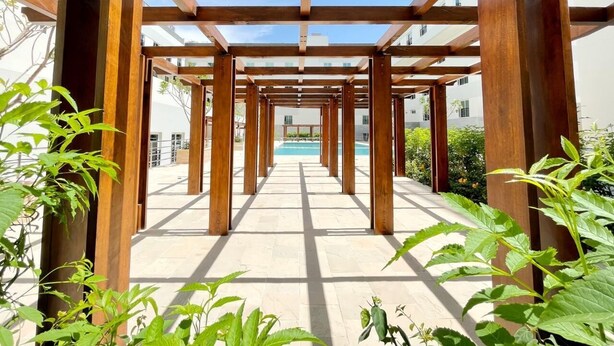 Una estructura de pergola de fusta amb vista despejada a una piscina al fons.
