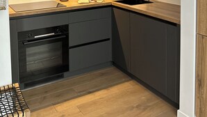 Una cocina compacta con armarios oscuros, encimera de madera, horno integrado y una ventana sobre el fregadero.