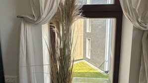 Una habitación con un ventanal grande, cortinas blancas y una planta en maceta.
