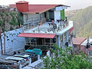 Un hotel con terraza en la azotea, zona de estar al aire libre y vistas del paisaje circundante.