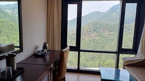 Une pièce comprenant un bureau, une chaise et offrant une vue sur un paysage montagneux grâce à de grandes fenêtres.