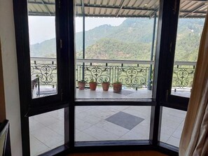 Une chambre avec vue sur un balcon agrémenté de plantes en pot et sur un paysage montagneux.