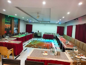 Un salón de conferencias con una larga mesa, sillas, un atril y una alfombra de diseño geométrico.