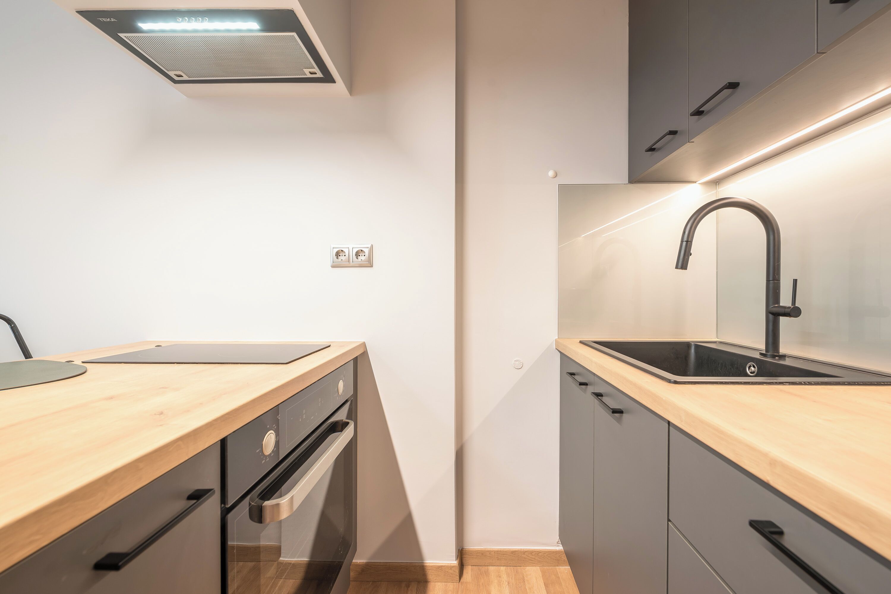 A modern kitchen with a wooden countertop, stainless steel appliances, and a sleek faucet.