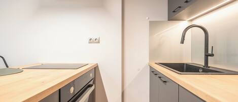 A modern kitchen with a wooden countertop, stainless steel appliances, and a sleek faucet.
