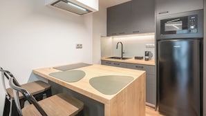 A modern kitchen with a central island, a built-in oven, and a refrigerator. - Newly Renovated Loft by Cloudkeys (Athens)