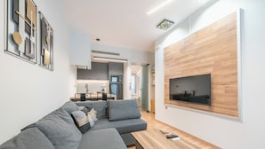 A modern living room with a grey sectional sofa, a wooden coffee table, and a mounted TV. - Newly Renovated Loft by Cloudkeys (Athens)