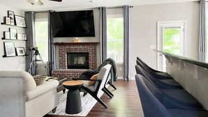 Ein Wohnzimmer mit Kamin, einer Couch, einem Sessel und einem Fernseher.