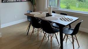 Een eetgedeelte met een houten tafel, zwarte stoelen en een hanglamp.