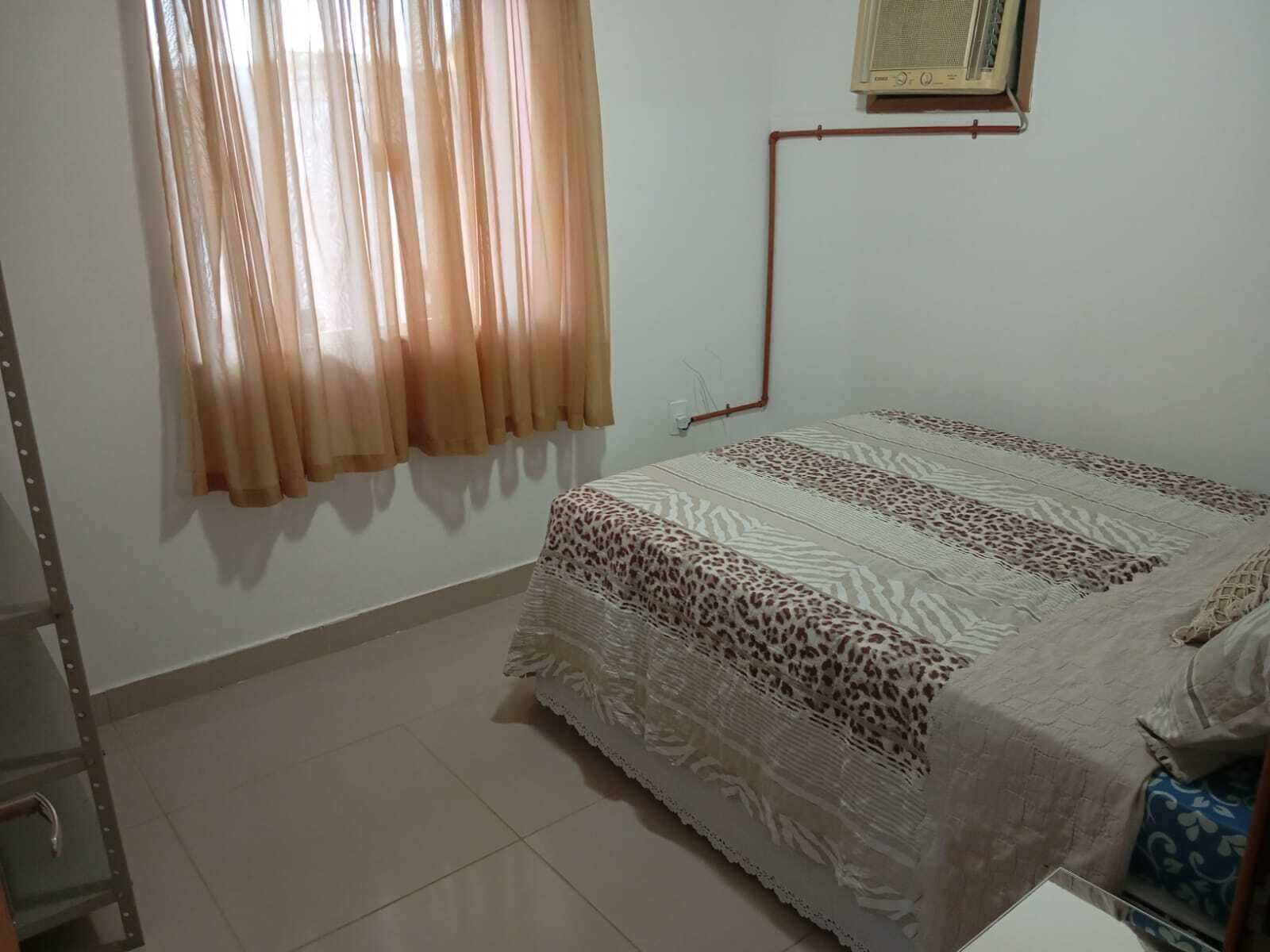 Een slaapkamer met een bed, een raam met gordijnen, een radiator en een deur.
