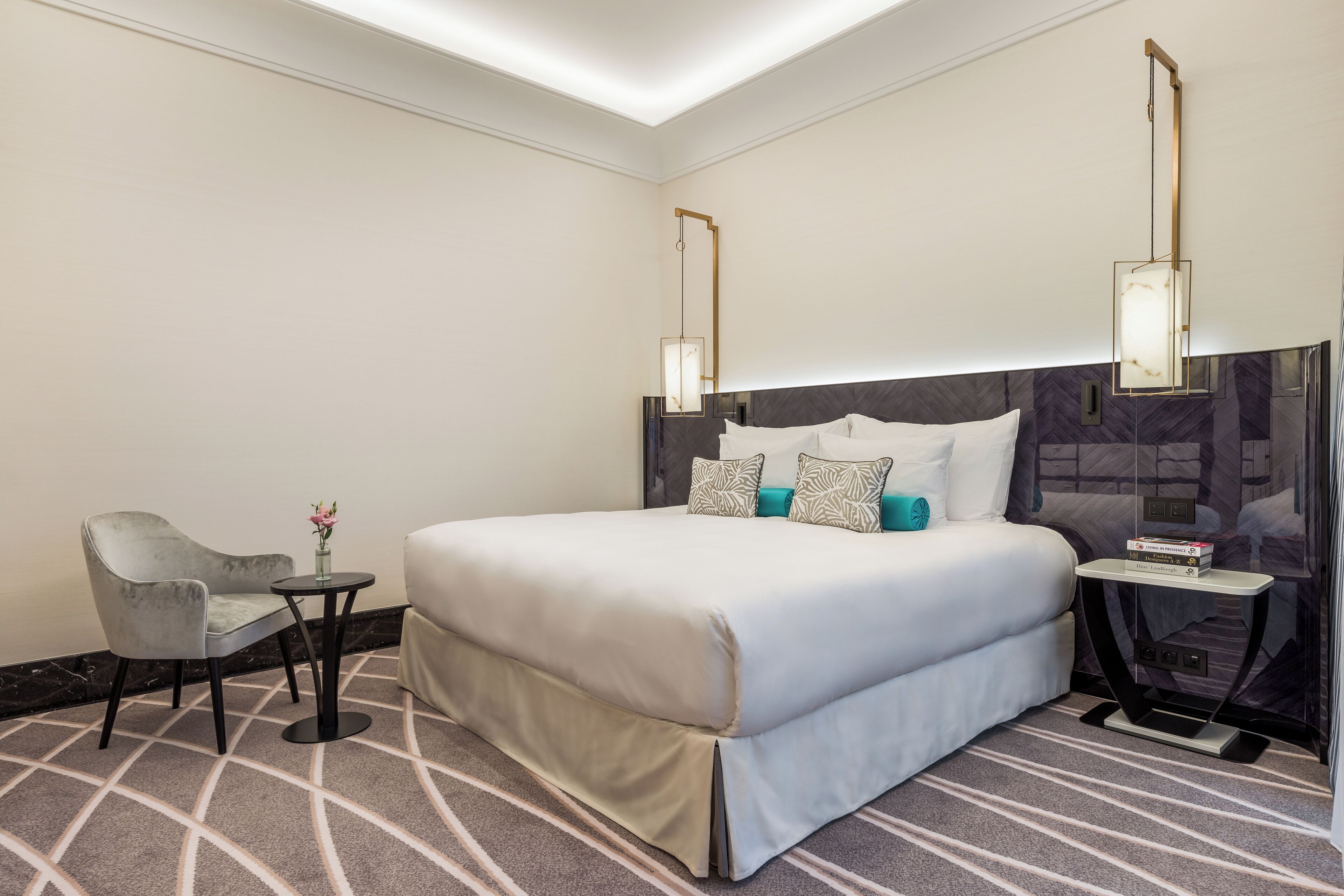 A hotel room with a large bed, a small table, a chair, and a nightstand.