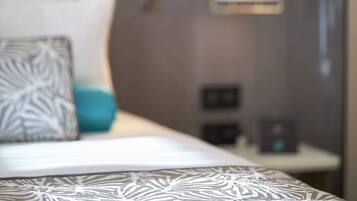 Un lit avec une couvre-lit à motifs, un oreiller à motifs géométriques et une table de chevet avec une lampe.