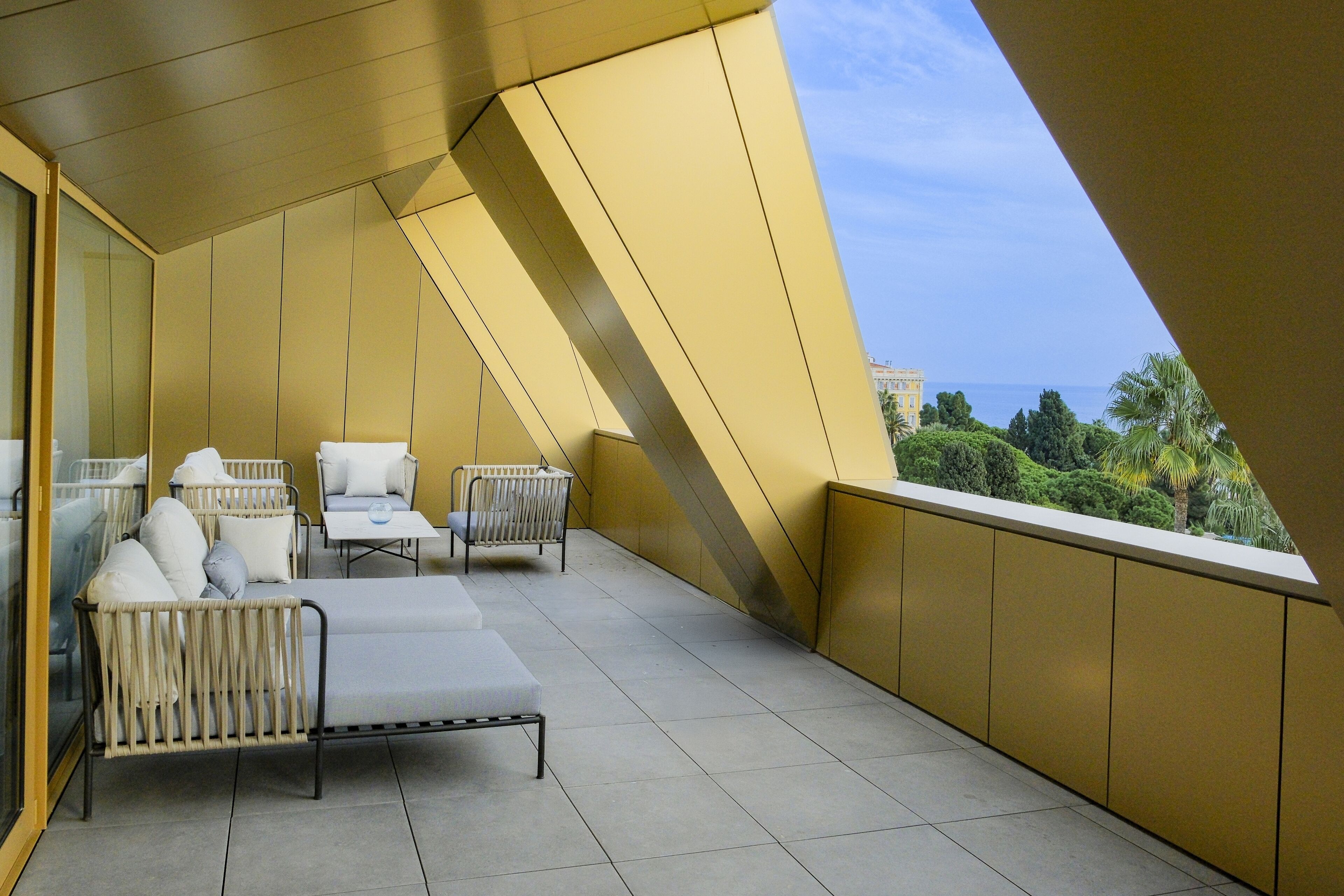 A balcony with a sofa, chairs, and a table, overlooking a scenic view.
