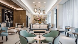 A modern hotel lobby with a central seating area, a bar, and a display of decorative items. - Maison Albar - Le Victoria (Nice)