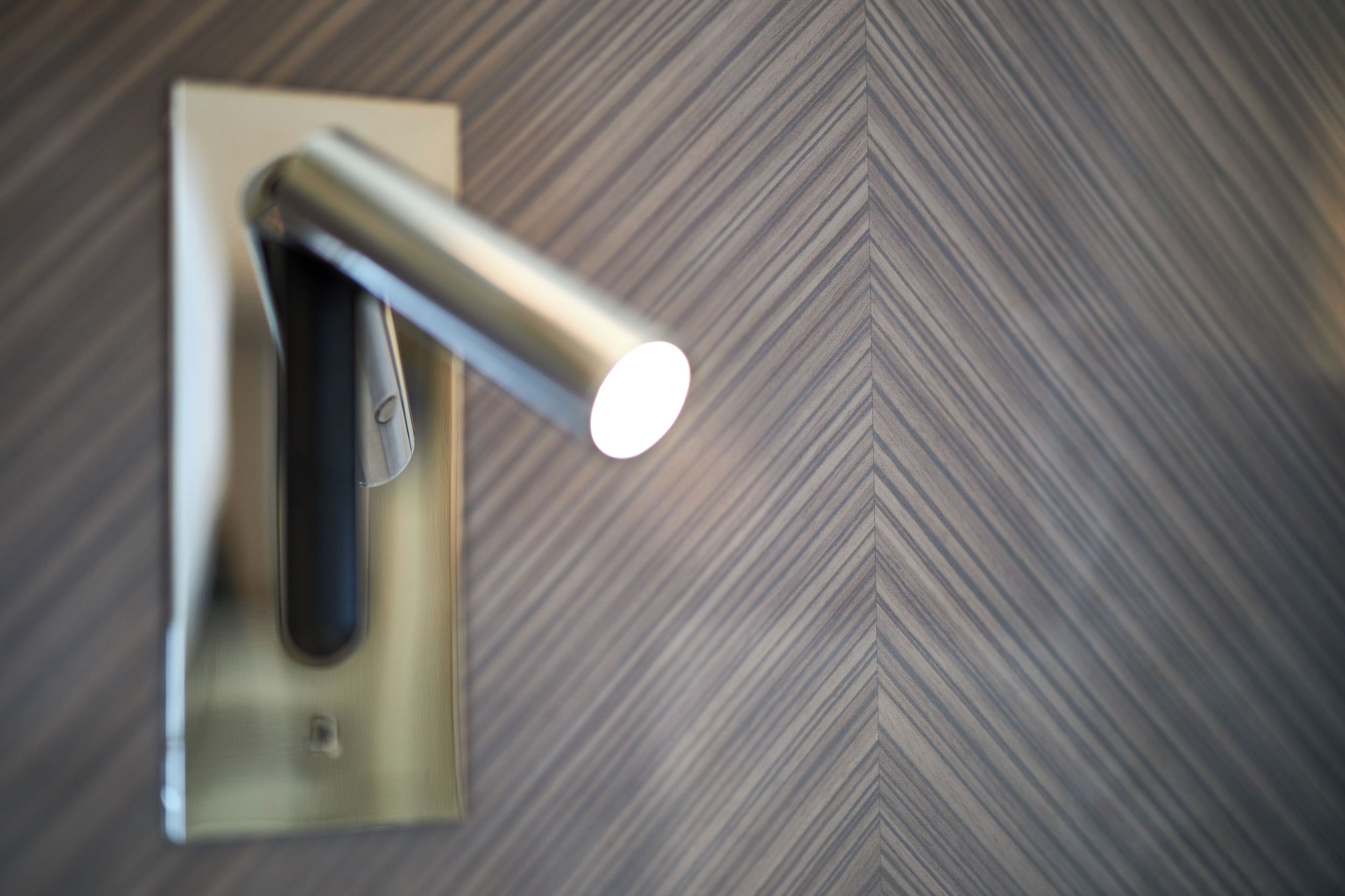 A wall-mounted light fixture with a metallic finish and a rectangular base.