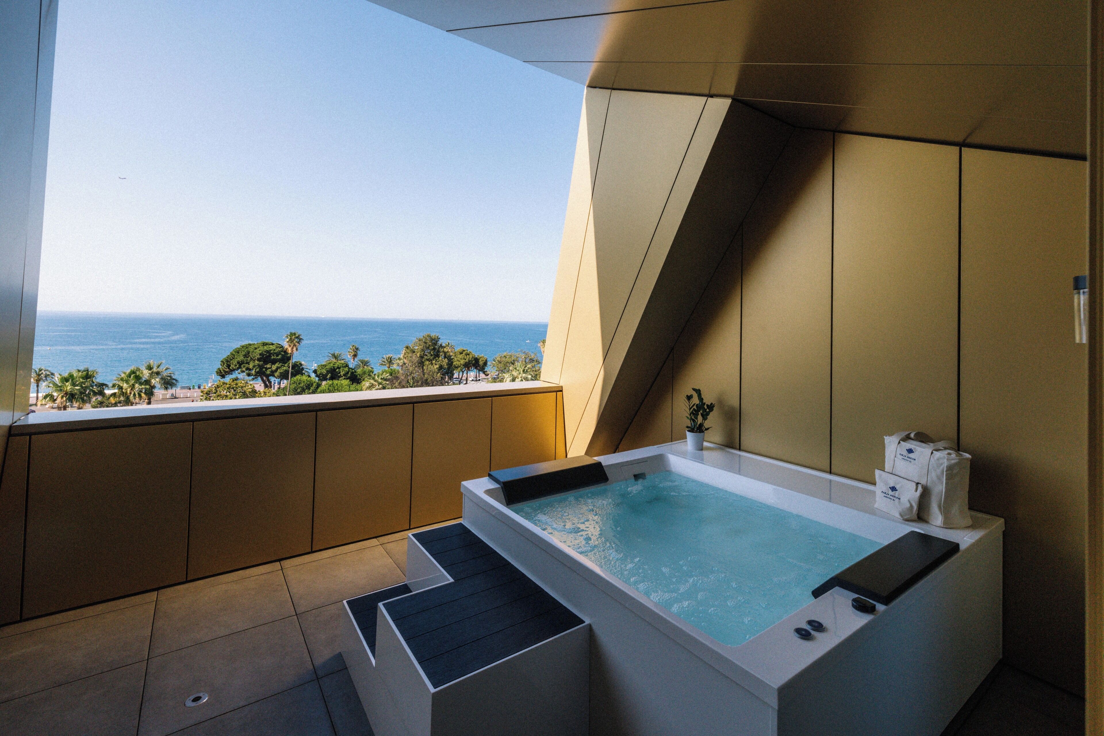 Une salle de bain moderne avec une baignoire, une vue sur l’océan et un balcon.
