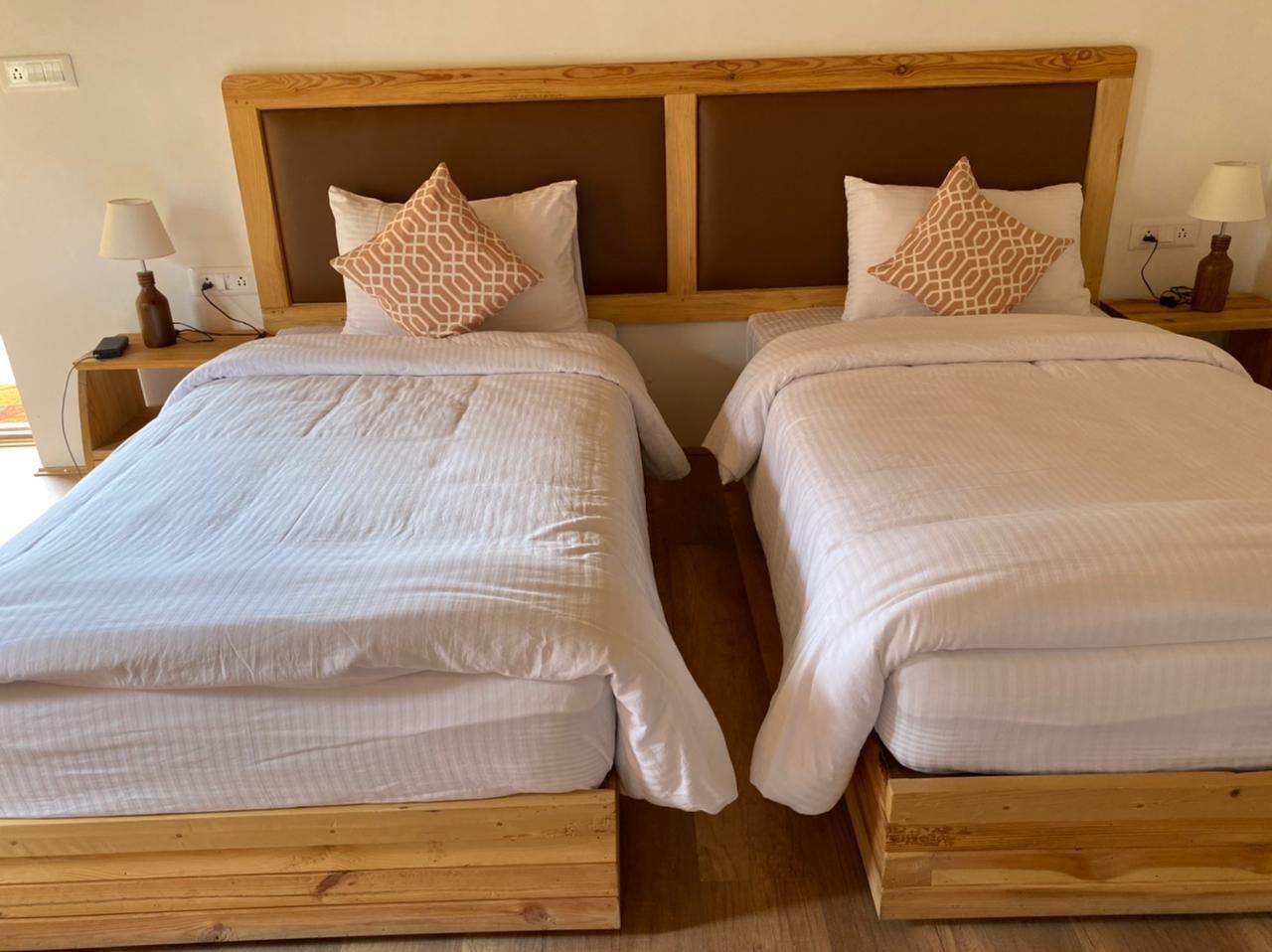 A double room with two single beds, each with a wooden headboard and white bedding.