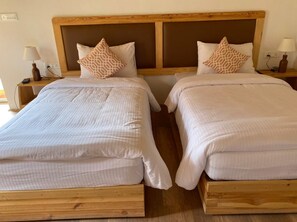 A double room with two single beds, each with a wooden headboard and white bedding.
