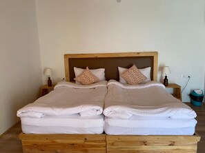 A double bed with a wooden frame, two bedside tables with lamps, and a trash bin.